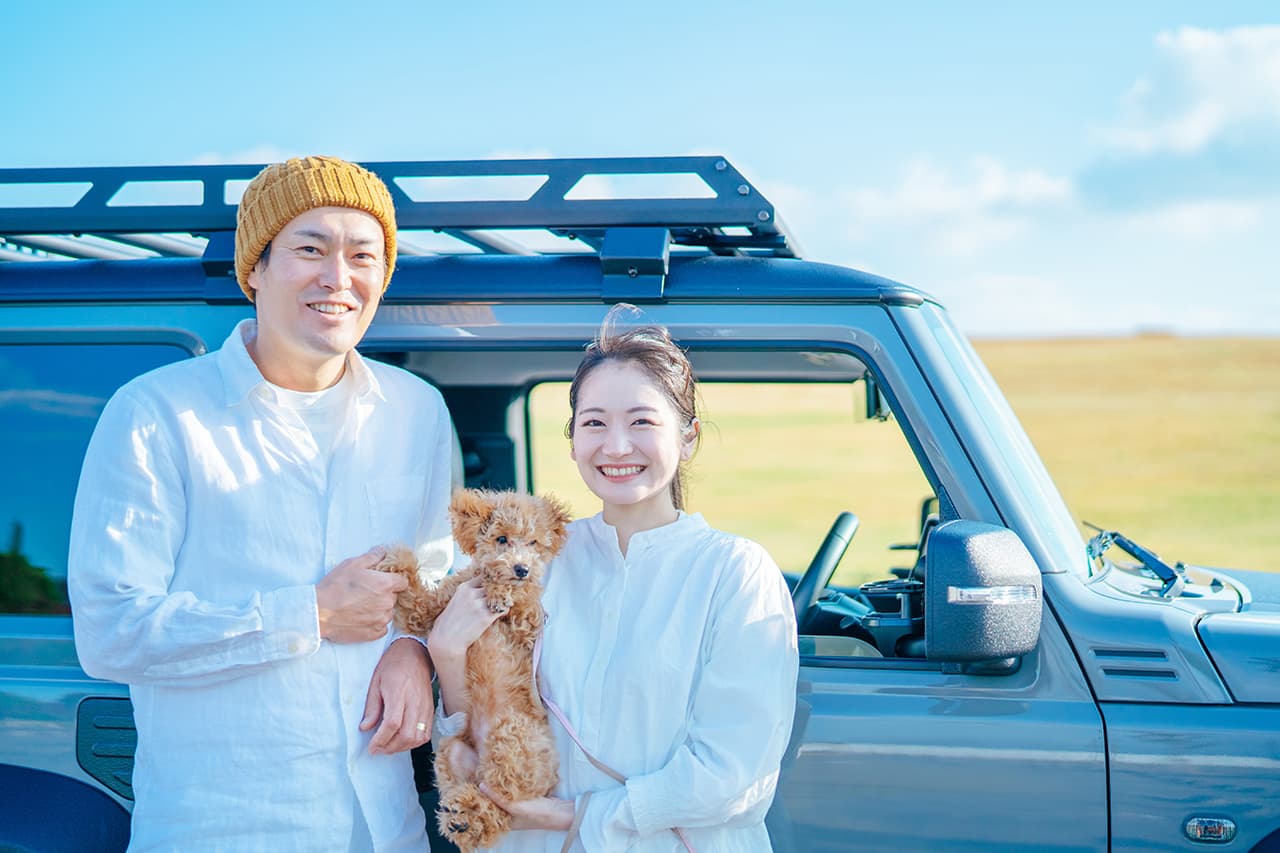 車の前で男女と犬が笑っている様子